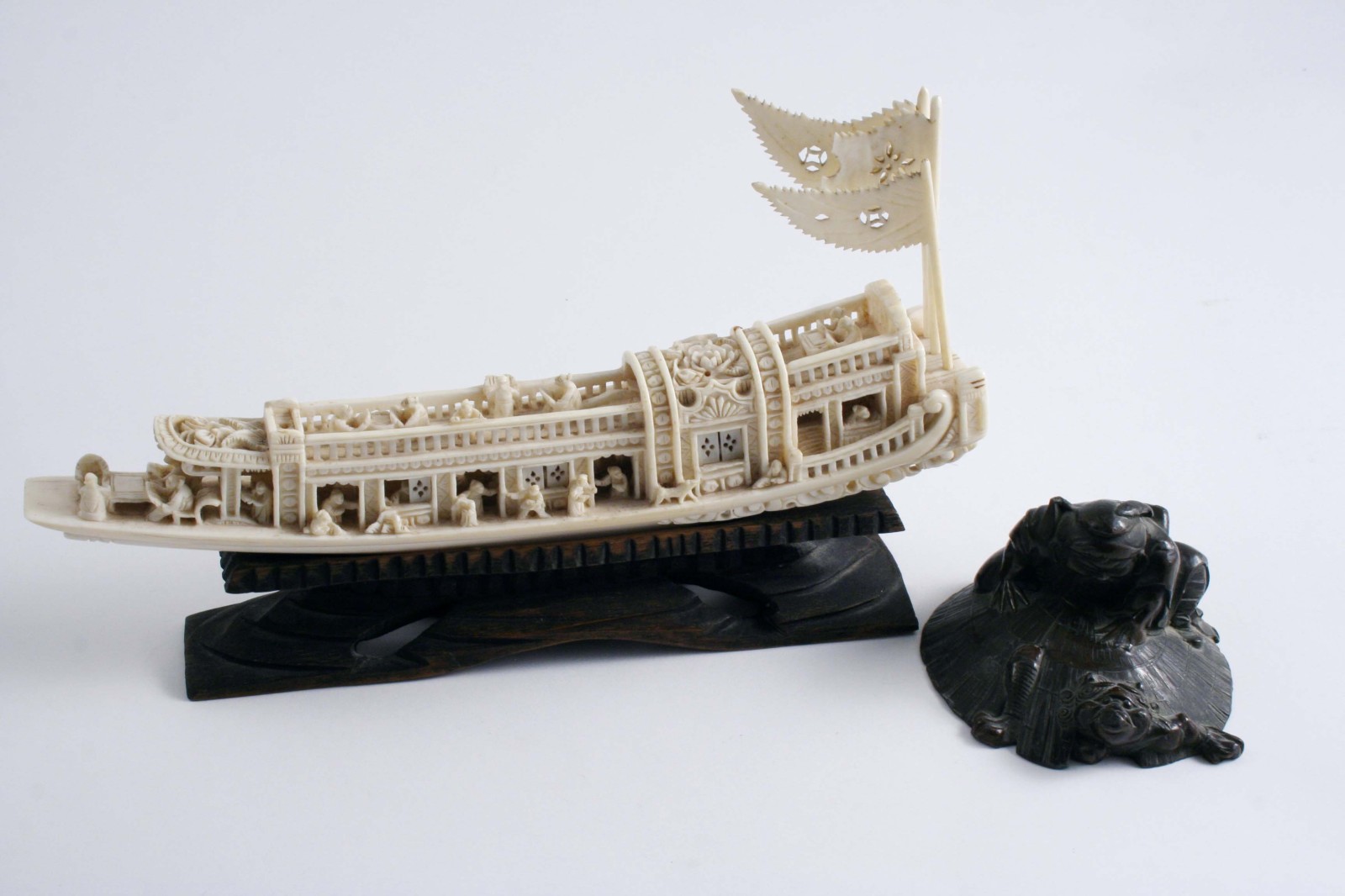 A CHINESE CARVED IVORY MODEL OF A BOAT with numerous figures, 19.5 cms with wood stand and a