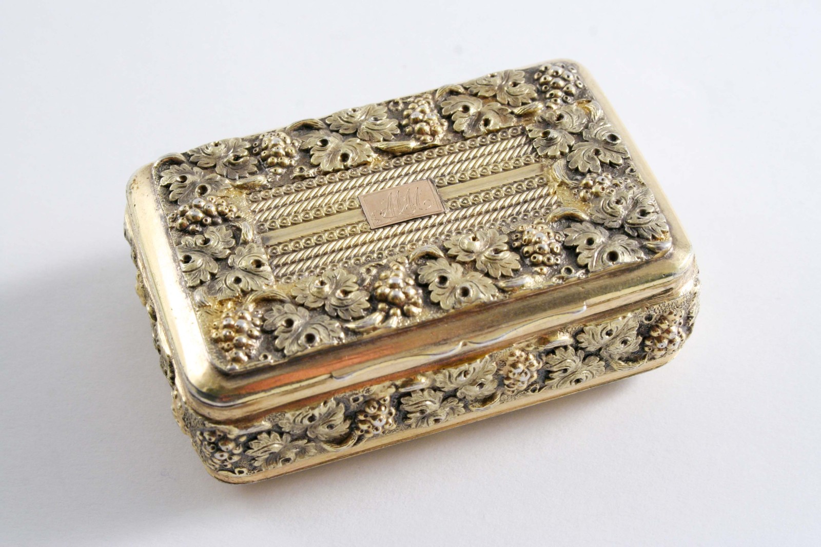 A GEORGE III SMALL SILVERGILT SNUFF BOX oblong with rounded corners decorated in relief around the