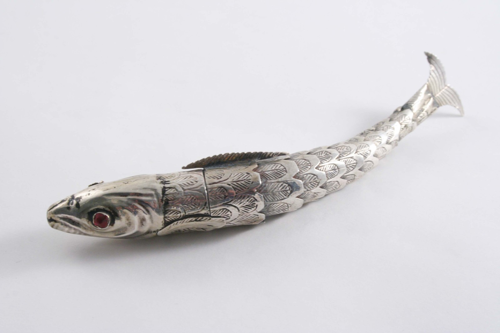 A 19TH CENTURY CONTINENTAL SMALL ARTICULATED FISH with one red glass eye, unmarked;  5.75"  (14.7