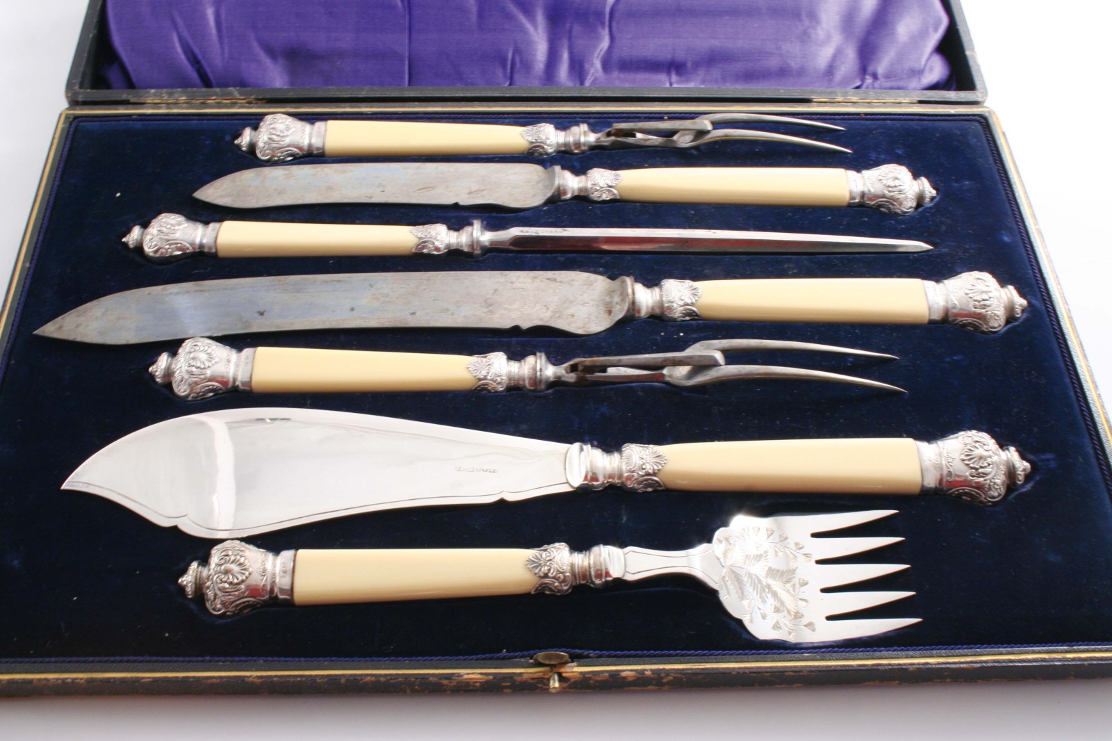 AN EDWARDIAN MOUNTED STEEL & PLATED CARVING SET with simulated ivory handles & embossed mounts