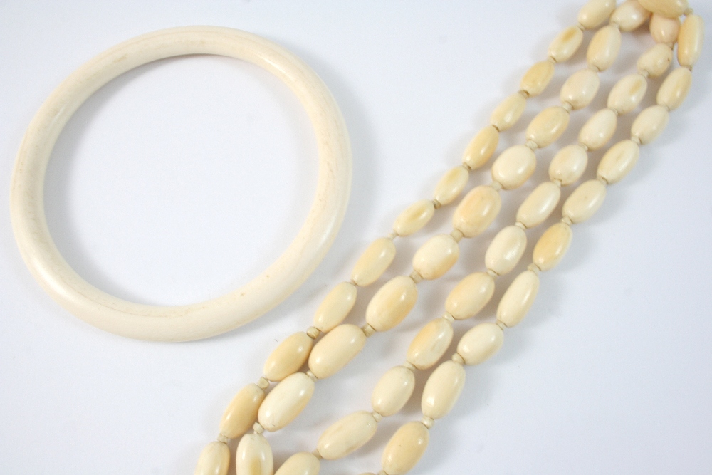 AN ANTIQUE IVORY BEAD NECKLACE formed with graduated oval-shaped ivory beads, 90cm. long, together