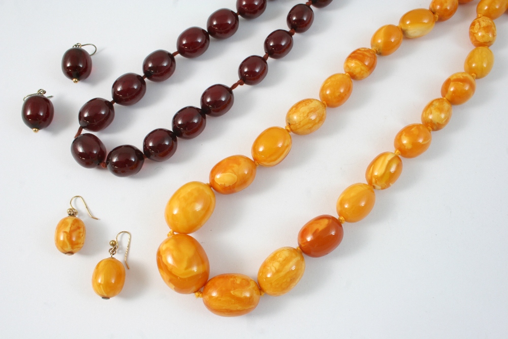 A GRADUATED AMBER BEAD NECKLACE formed with graduated oval beads, 88cm. long, together with