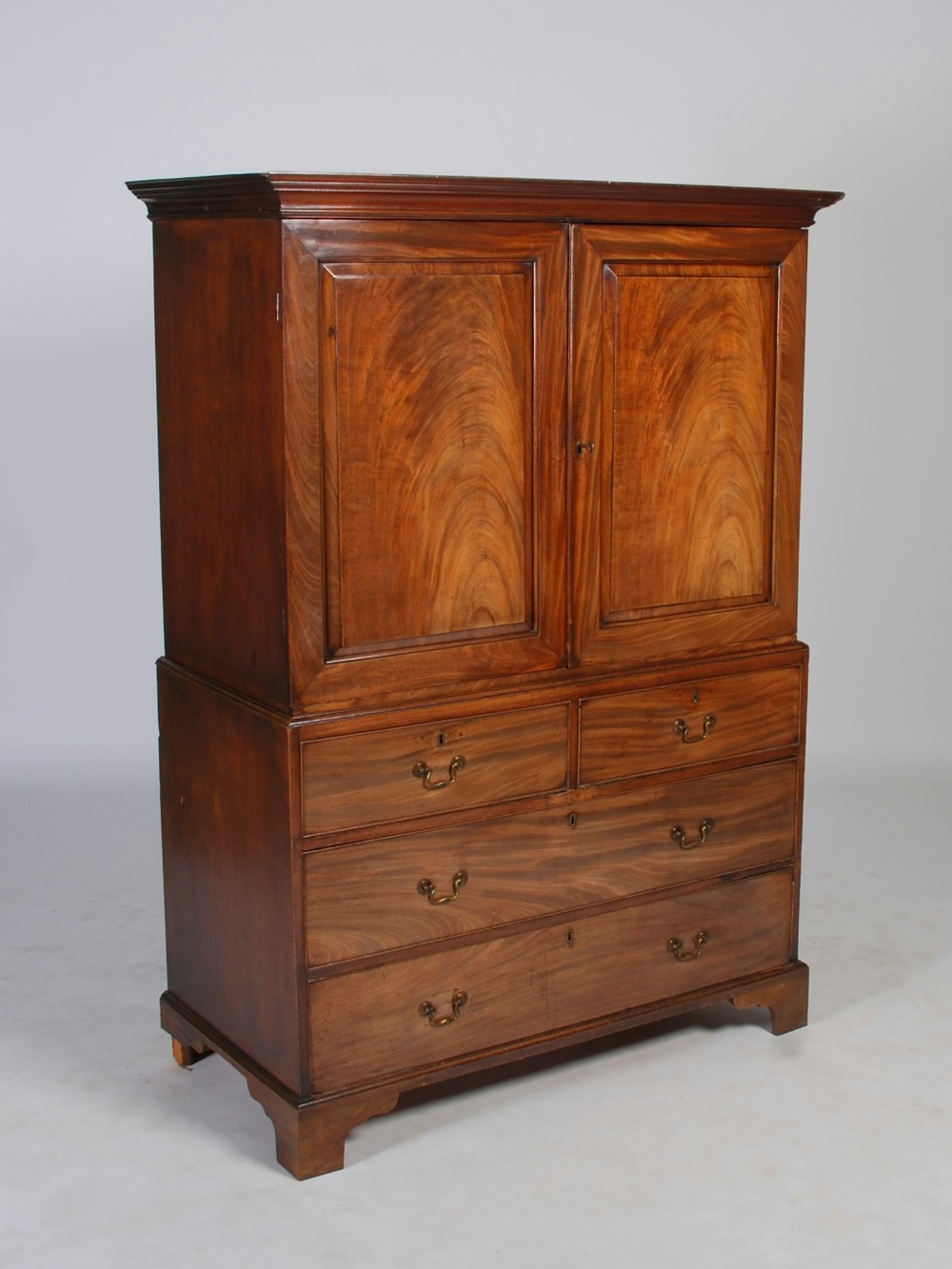 A George III mahogany linen press, the moulded cornice above a pair of panelled cupboard doors,