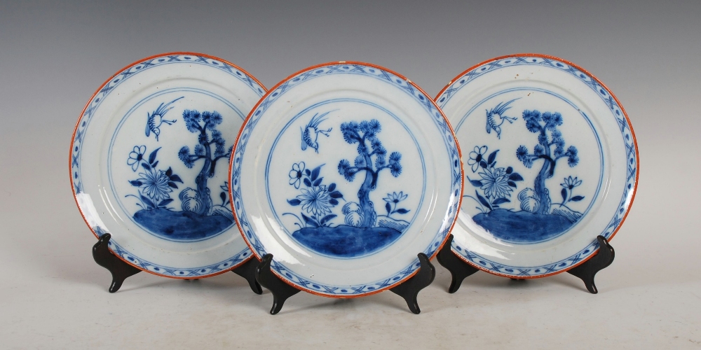 A set of three 19th century Delft plates, decorated with a garden of flowers, pine tree and bird, - Image 2 of 10