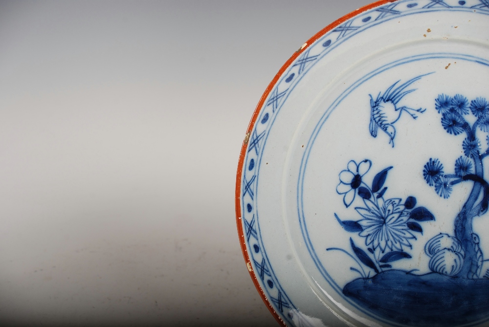 A set of three 19th century Delft plates, decorated with a garden of flowers, pine tree and bird, - Image 9 of 10