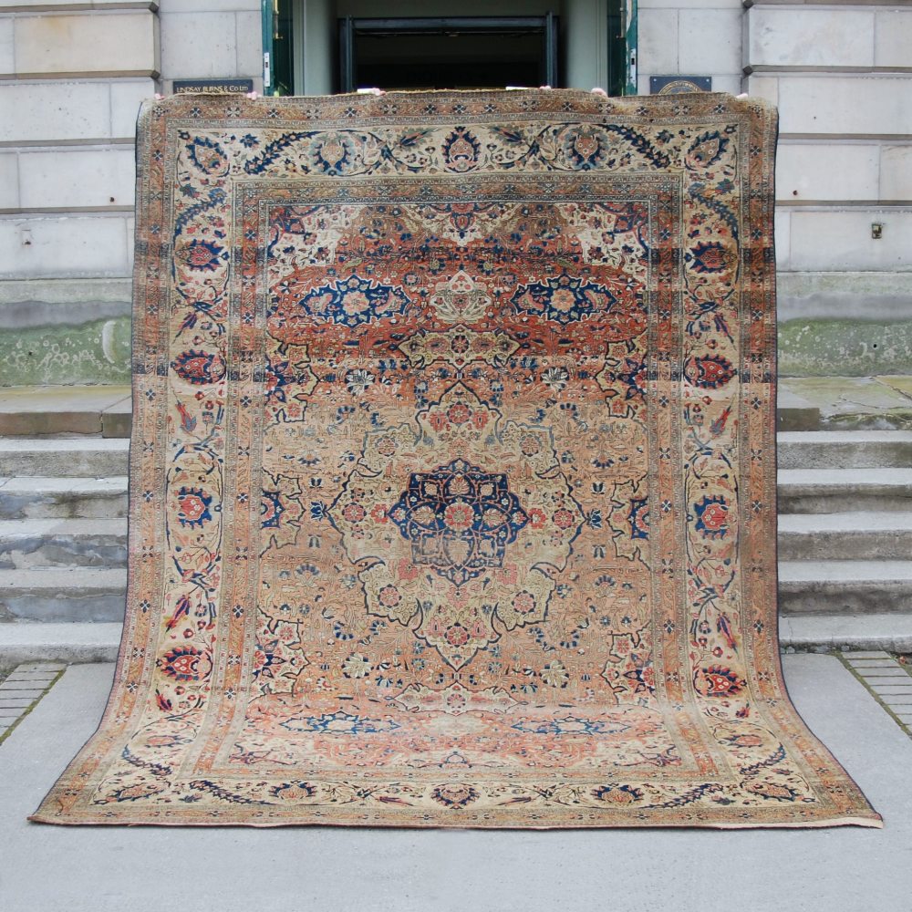 An antique Persian carpet, the abrashed madder field centred with a blue floral medallion within