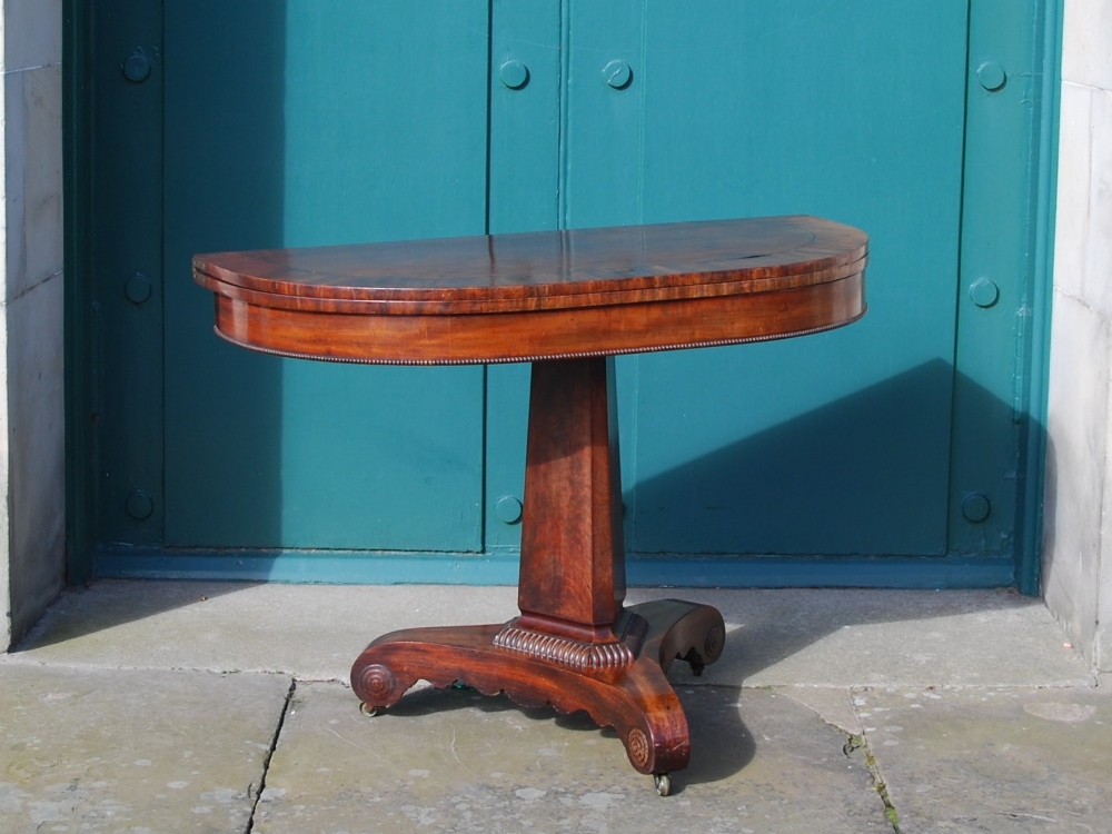 A Victorian mahogany and ebony strung pedestal tea table, the hinged, revolving D-shaped top above a