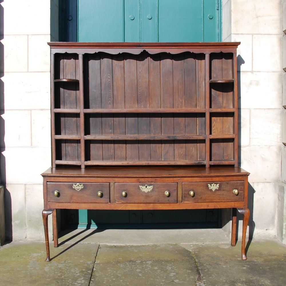 An 18th century and later oak dresser, the moulded cornice and shaped frieze above three open
