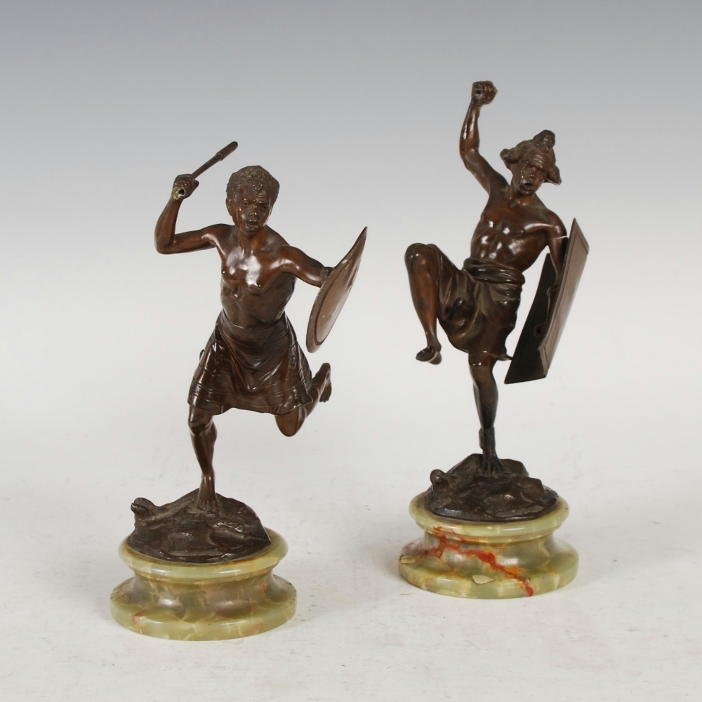 A pair of early 20th century bronzed spelter figures of tribal warriors, mounted on circular onyx