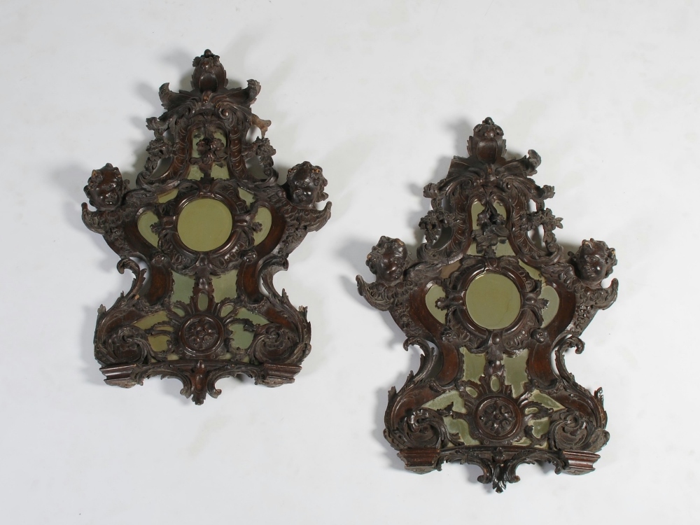 A pair of 18th/ 19th century carved wood, possibly walnut, Rococo style wall mirrors, carved with