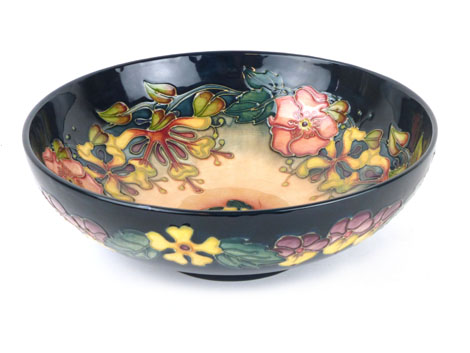 A Moorcroft fruit bowl in the honeysuckle pattern on a dark green-blue ground, green painted W.M