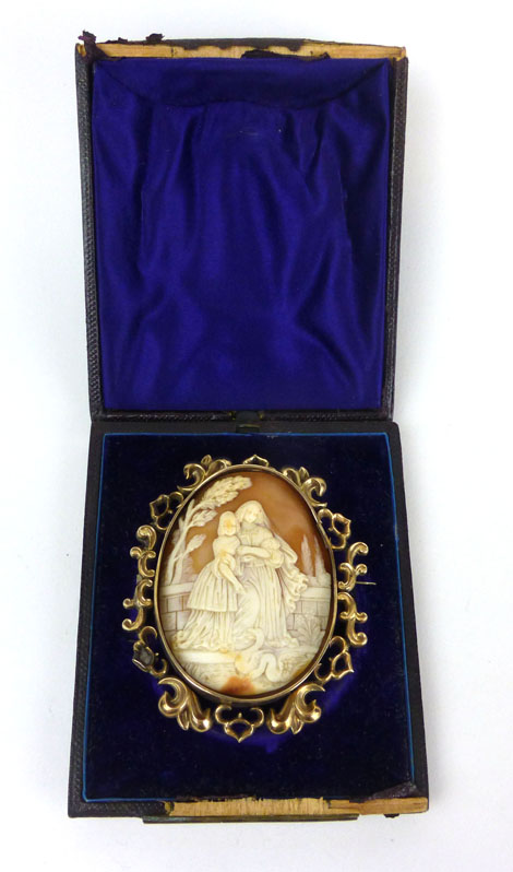 A yellow metal mounted oval cameo brooch depicting a mother and her daughter feeding swans in a