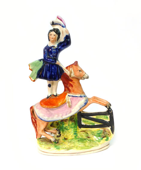 A Staffordshire equestrian circus group modelled as a girl standing on a horse taking a fence, h.