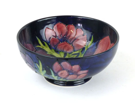 A Moorcroft footed bowl in the anemone pattern on a blue ground, green painted W.M initials and