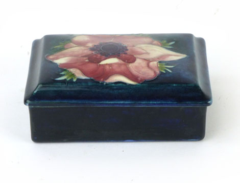 A Moorcroft box and cover of rectangular form in peony pattern on a blue ground, applied paper label