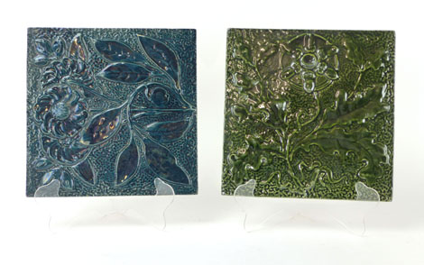 Two Burmantofts Faience tiles with a molded floral design under a iridescent green or blue glaze,