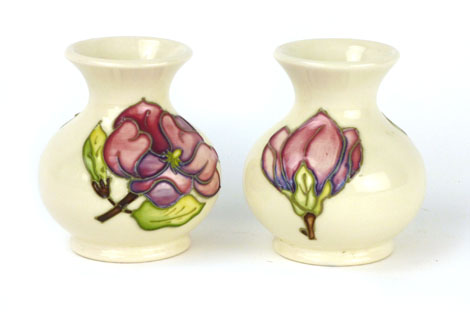 A pair of Moorcroft vases of squat baluster form in the magnolia pattern on a cream ground,