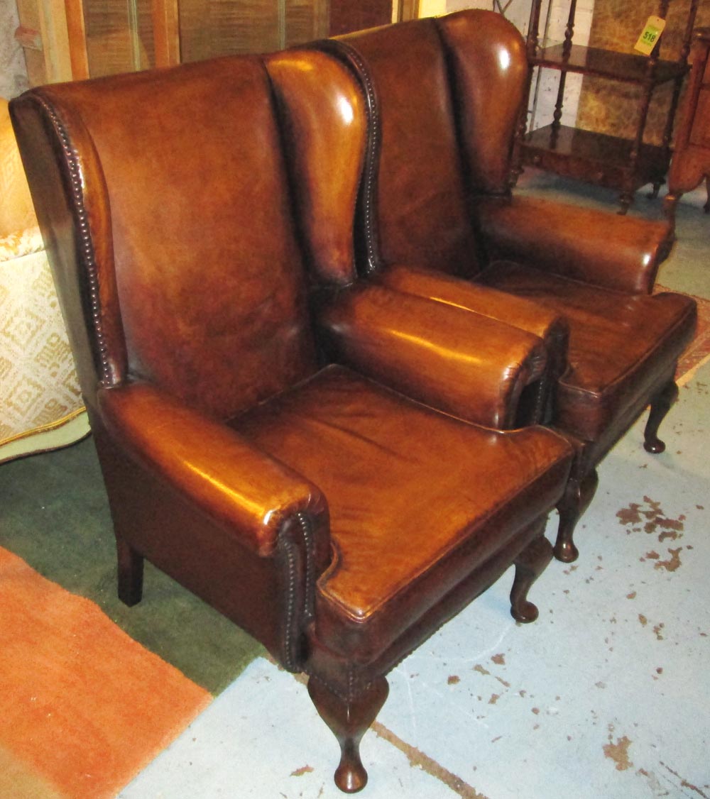 WING ARMCHAIRS, a pair, Queen Anne style faded tan brown leather with cabriole supports, 75cm W. (