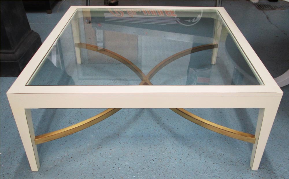 LOW  TABLE, cream painted with a square glass top and a gold painted curved X stretcher, 110cm x