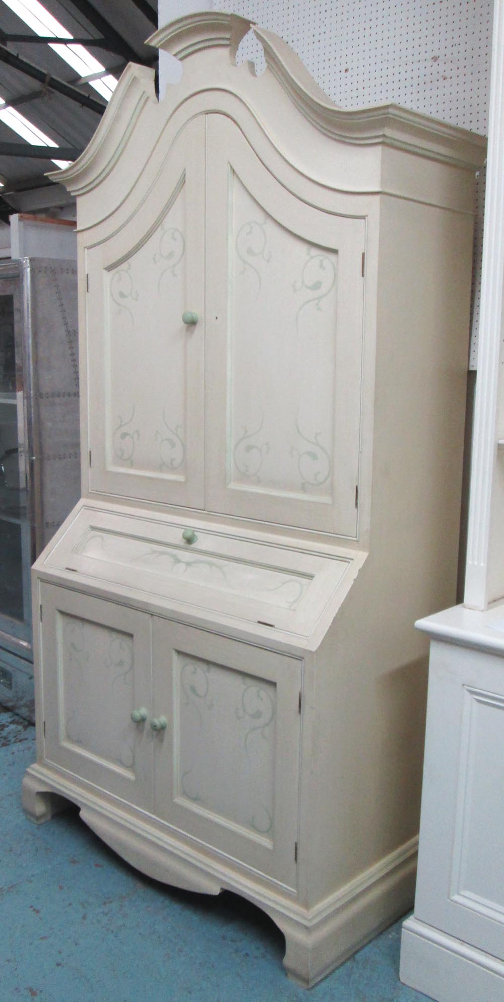 BOOKCASE/CABINET, in a cream finish with a shaped pediment and a pair of panelled cupboard doors