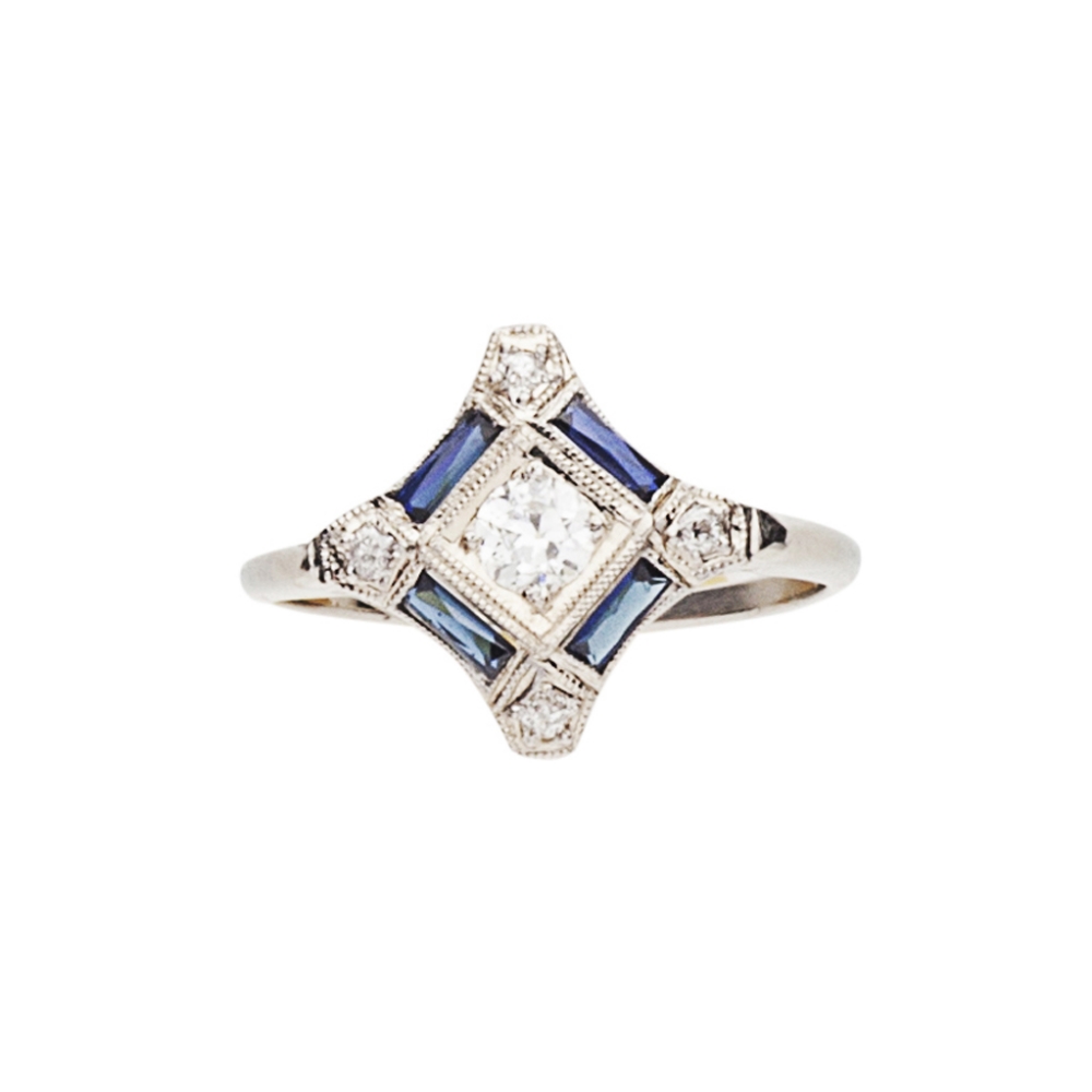 An Edwardian style diamond and sapphire ringthe central circular cut diamond in a square setting,