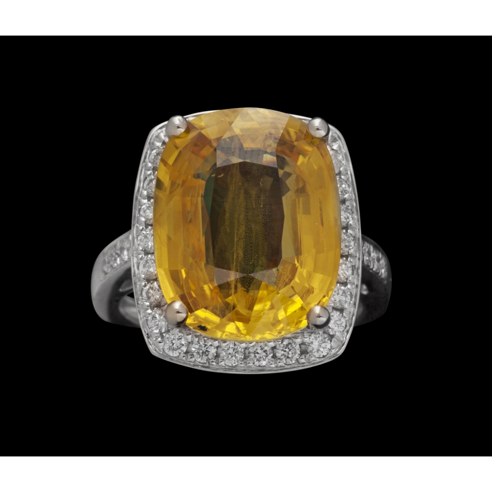 A yellow sapphire and diamond set cluster ringclaw set with an oval mixed cut yellow sapphire, in a