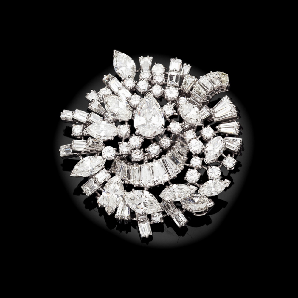 An all-diamond cluster broochof shaped circular design, claw set throughout with graduated pear,