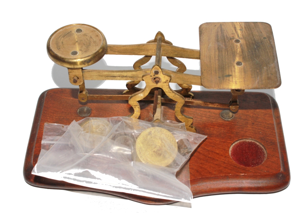 An early 20th century brass weighing scales with weights on a shaped mahogany base