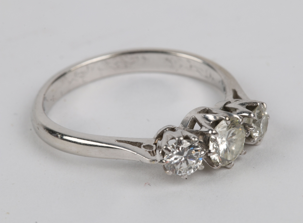 A WHITE METAL, probably platinum, ring set with a central diamond flanked by a further diamond to
