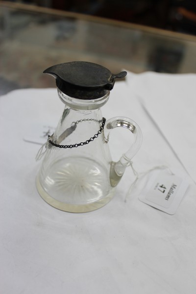 AN EARLY 20TH CENTURY GLASS AND SILVER MOUNTED TOT DECANTER with star cut bottom and silver label