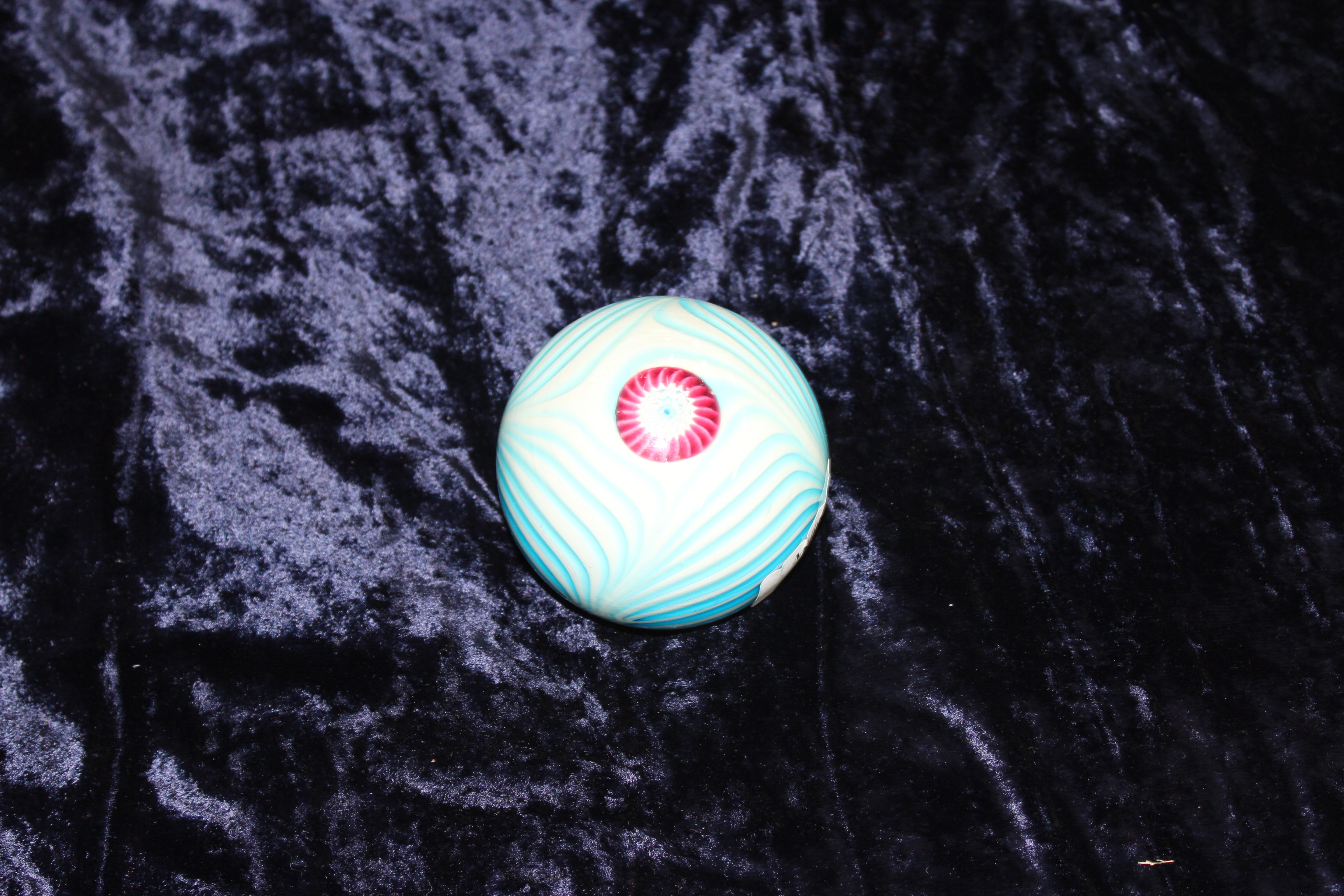 A GLASS PAPERWEIGHT of blue and white swirl decoration and central cane 8cm diameter