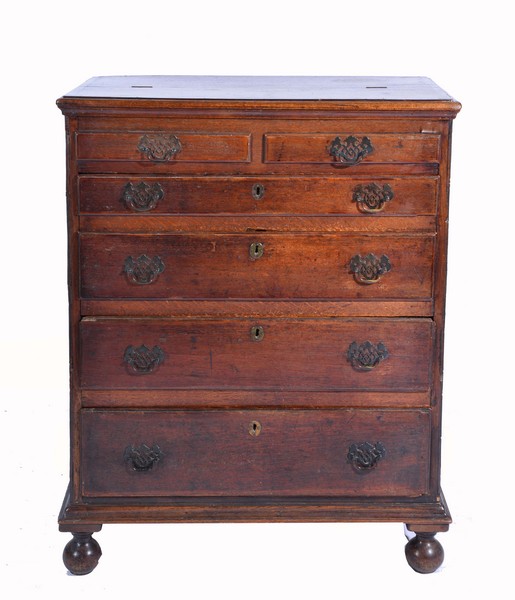 AN 18TH CENTURY OAK CHEST with a lifting top, two false short drawers, four long graduated drawers,