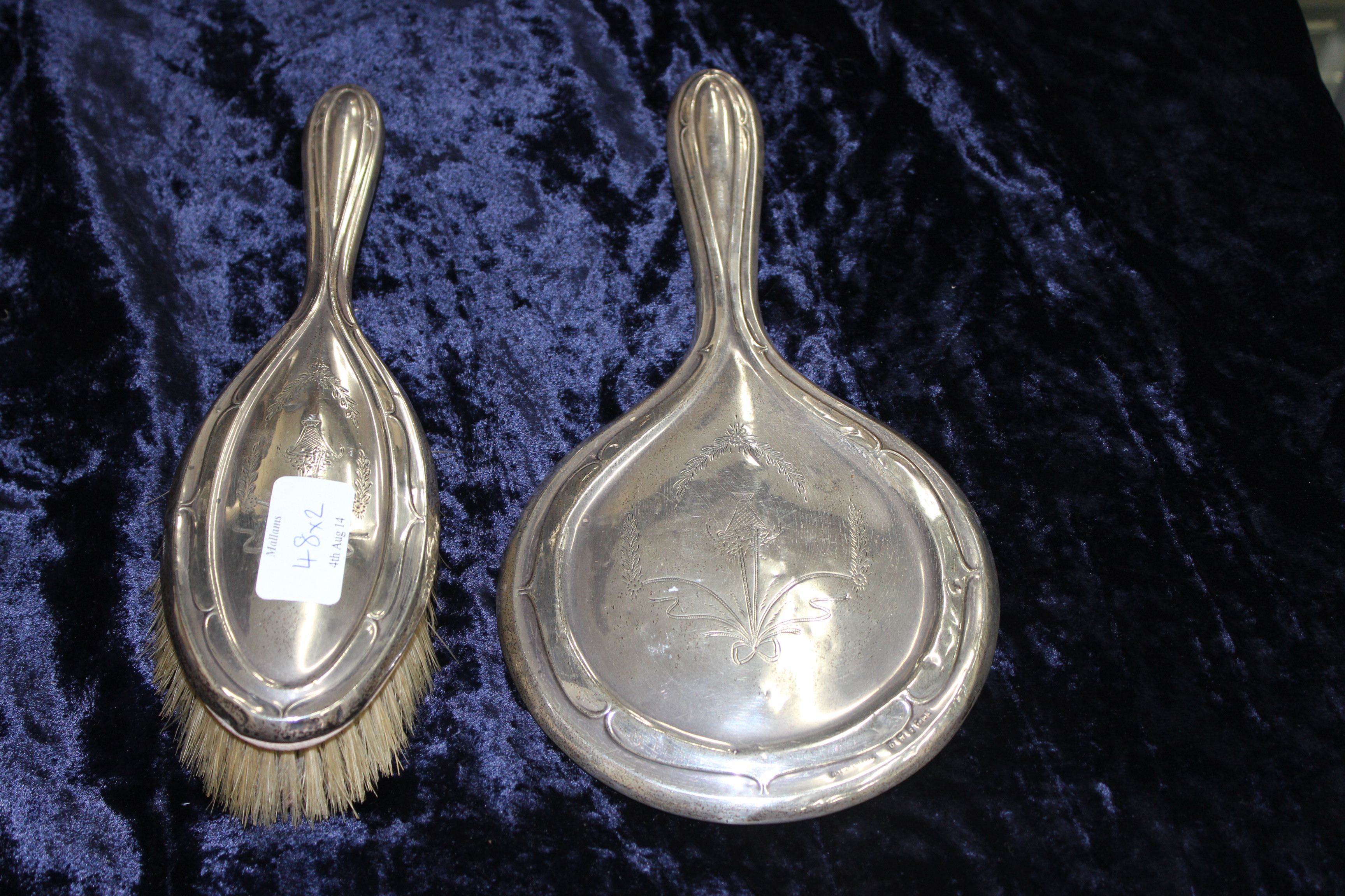 AN EARLY 20TH CENTURY SILVER BACKED DRESSING TABLE MIRROR together with a matching brush (2)