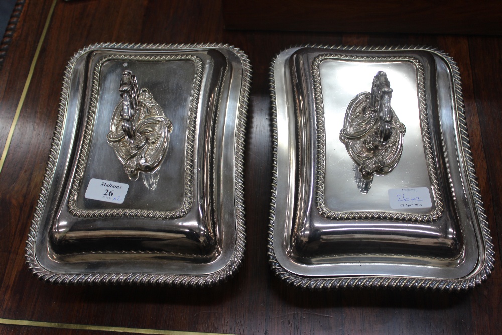 A PAIR OF SILVER PLATED ENTREE DISHES with gadrooned edges and scroll handles 29cm wide