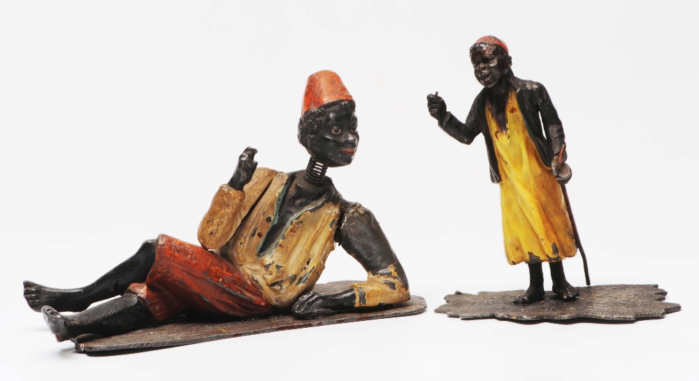 A SPELTER SCULPTURE of a north African gentleman resting on a mat, 16cm long together with a small