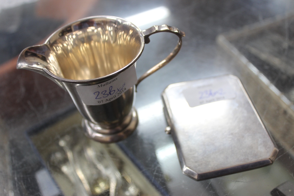 AN EARLY 20TH CENTURY SILVER CIGARETTE CASE together with a small silver cream jug standing on a