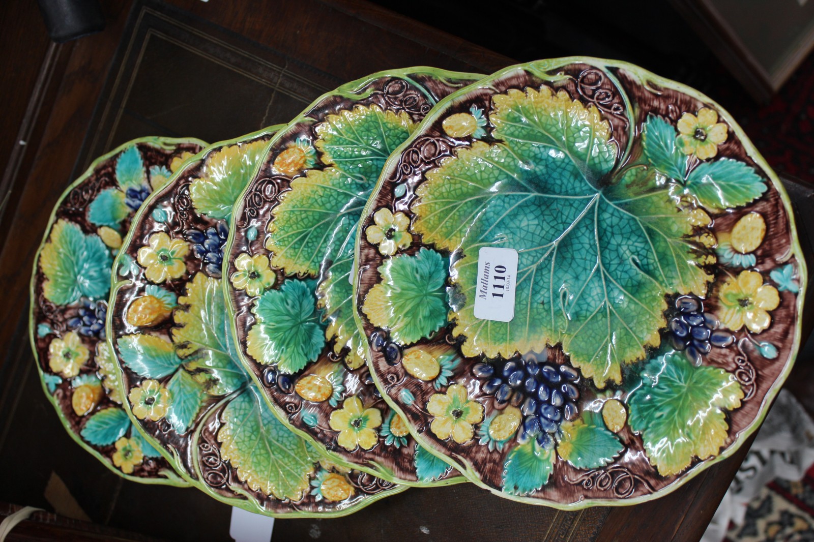 A SET OF FOUR VICTORIAN MAJOLICA VINE AND STRAWBERRY MOULDED PLATES, back stamp to the reverse for