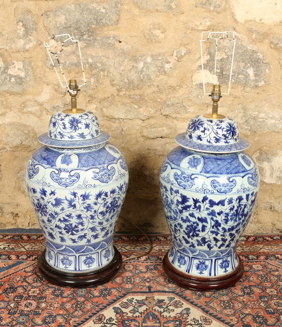 A PAIR OF LARGE CHINESE PORCELAIN BLUE AND WHITE LAMPS of baluster form with covers on hardwood