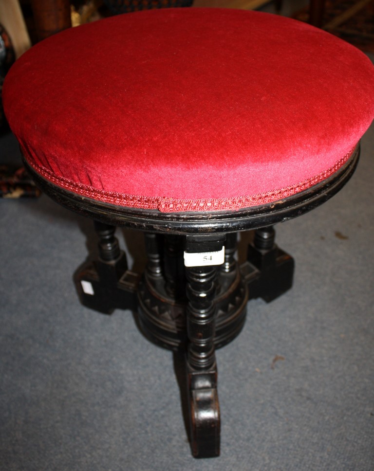 A GILLOWS AESTHETIC MOVEMENT EBONISED MUSIC STOOL with a revolving upholstered top and turned