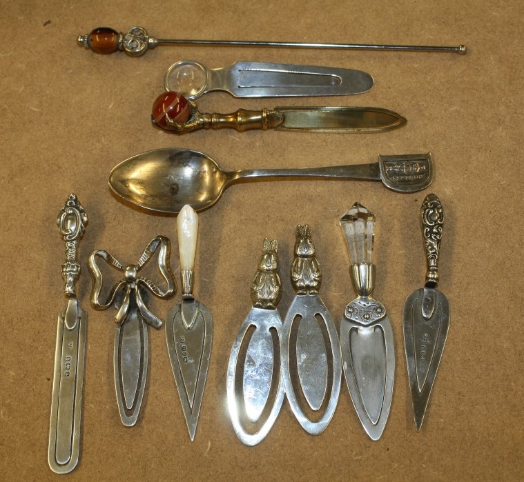 A COLLECTION OF EIGHT SILVER BOOK MARKS; a brass book mark; a silver spoon; and a swizzle stick (