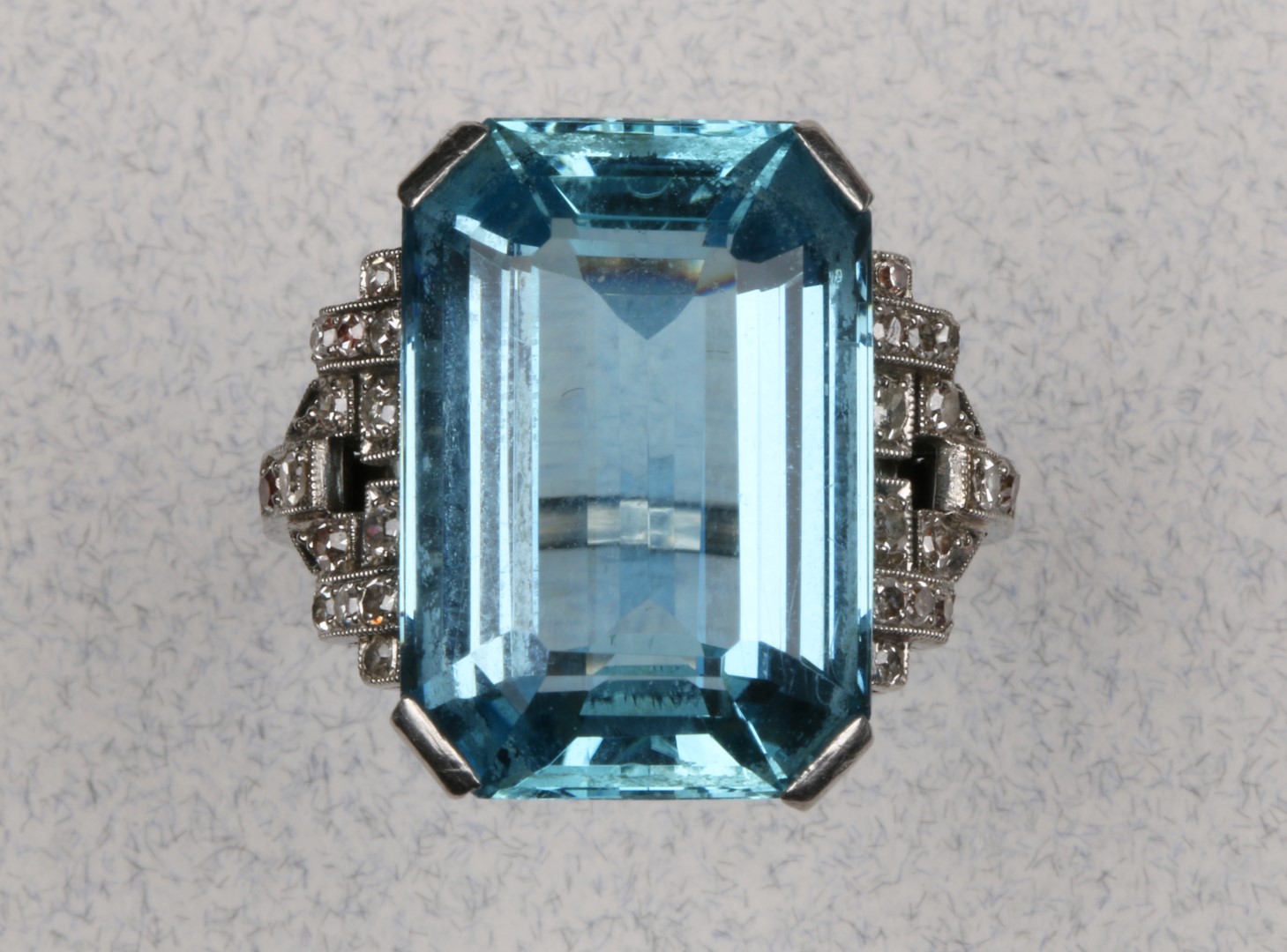 AN AQUAMARINE AND DIAMOND SET DRESS RING, emerald cut aquamarine set with four claws and flanked by