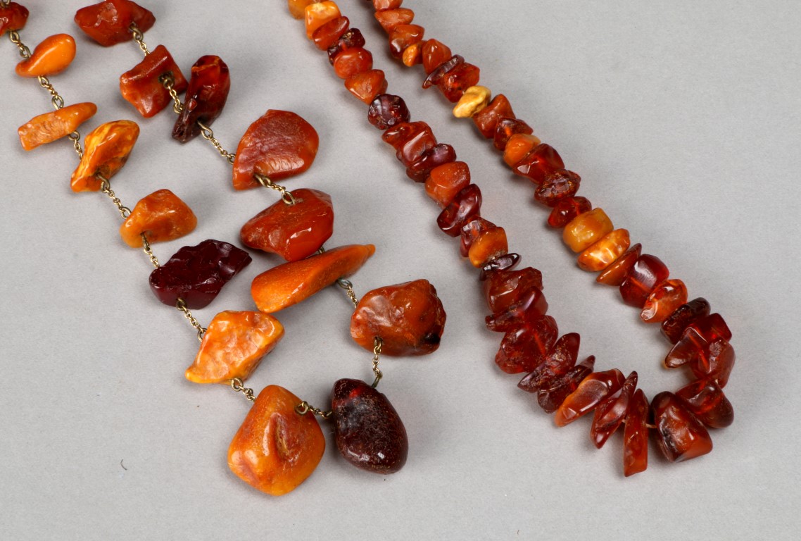 A GRADUATED ROUGH CUT AMBER BEAD NECKLACE with varying colours, 16" long; and a similar necklace