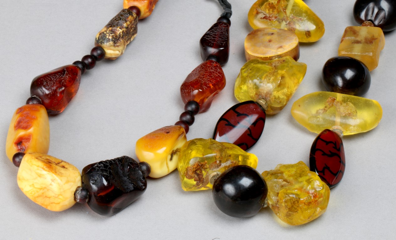 A ROUGH CUT GRADUATED AMBER BEAD NECKLACE with varying coloured beads and a further necklace with