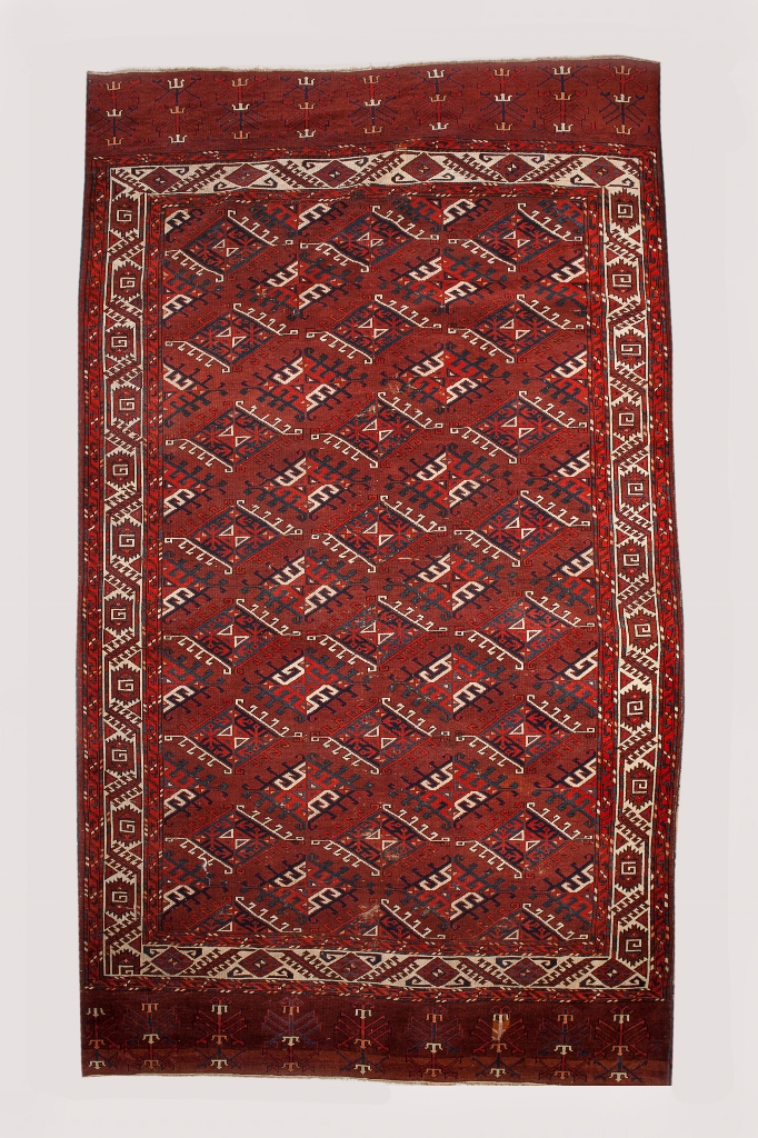 A YOMUT MAIN CARPET with rows of hooked medallions on a dark red ground, 186 x 313cm