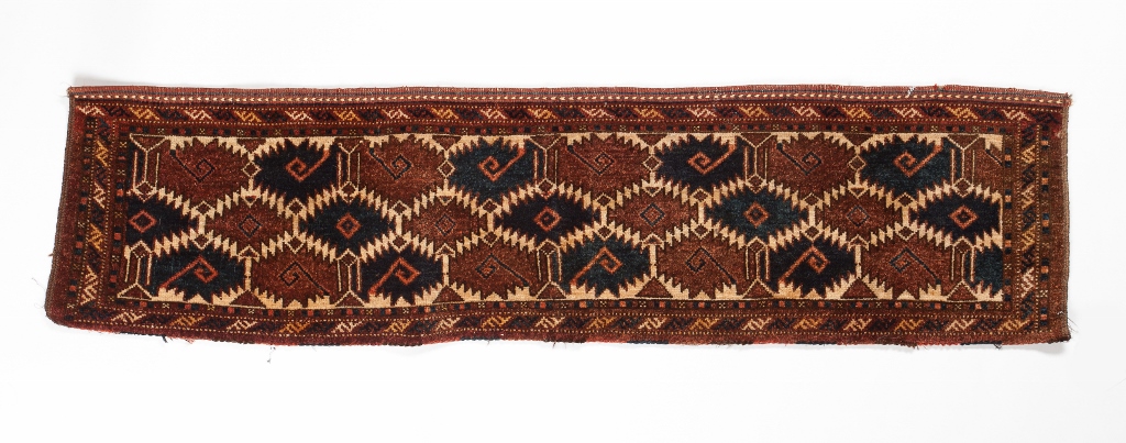 A TURKOMAN ERSARI TORBA with interlinked serrated medallions on a dark red ground, 38 x 146cm