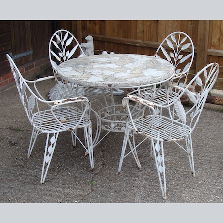 A white painted and reconstituted stone patio table, 90cm diameter, together with four chairs