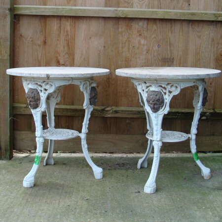 A pair of white painted cast iron garden tables, each with a circular marble top, 64cm