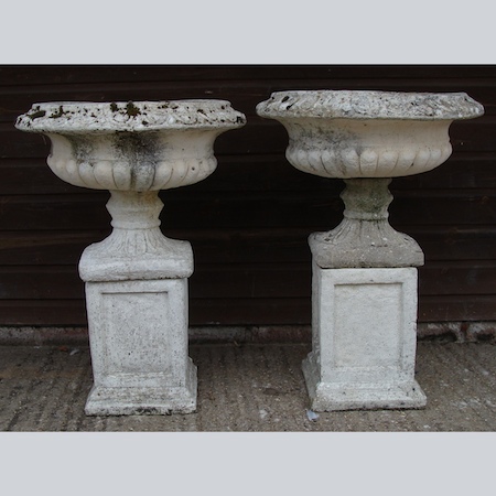 A pair of reconstituted stone garden urns, on pedestal bases, 75cm tall