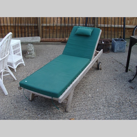 A teak garden lounger, with a loose cushion, together with another