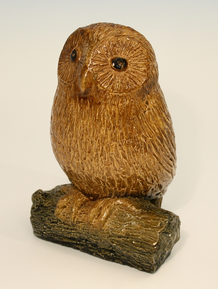 A 19th century pottery owl modelled perched upon a section of log, golden brown glaze with large